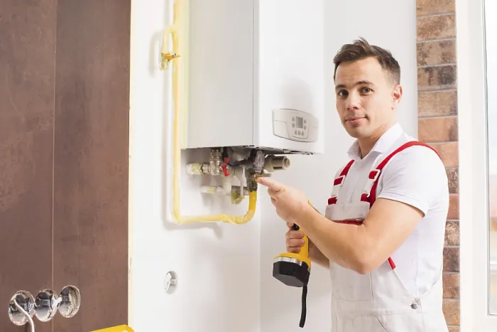 Gerahmter Druck : Die Seitenansicht eines jungen Installateurs, der einen Boiler installiert. Gerahmter Druck : Die Seitenansicht eines jungen Installateurs, der einen Boiler installiert.