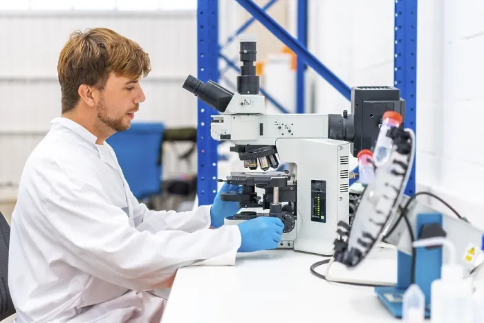Gerahmter Druck : Seitenansicht eines jungen Wissenschaftlers, der ein Mikroskop benutzt, um Proben in einem Krebsforschungslabor zu analysieren. Gerahmter Druck : Seitenansicht eines jungen Wissenschaftlers, der ein Mikroskop benutzt, um Proben in einem Krebsforschungslabor zu analysieren.