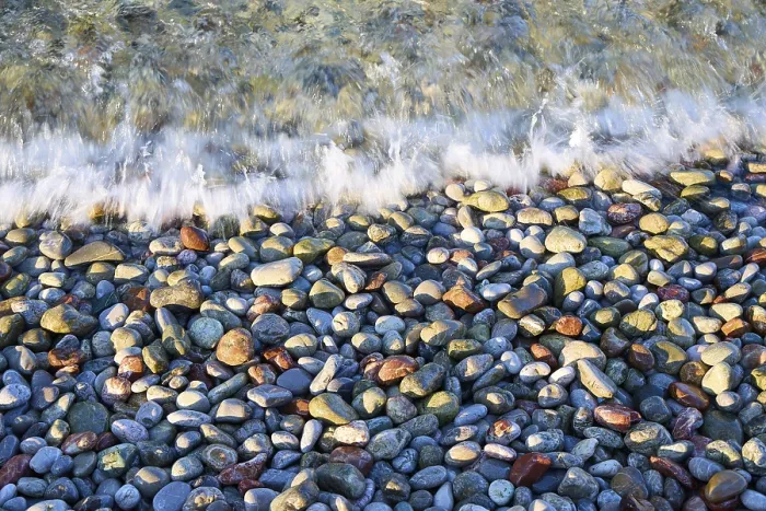 Gerahmter Druck : Wellen schlagen gegen einen Kieselstrand, der Texturen und Farben erzeugt.