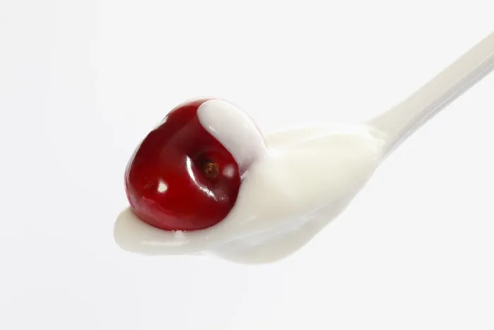 Gerahmter Druck : Weißer Plastiklöffel mit Joghurt und einer Kirsche. Gerahmter Druck : Weißer Plastiklöffel mit Joghurt und einer Kirsche.