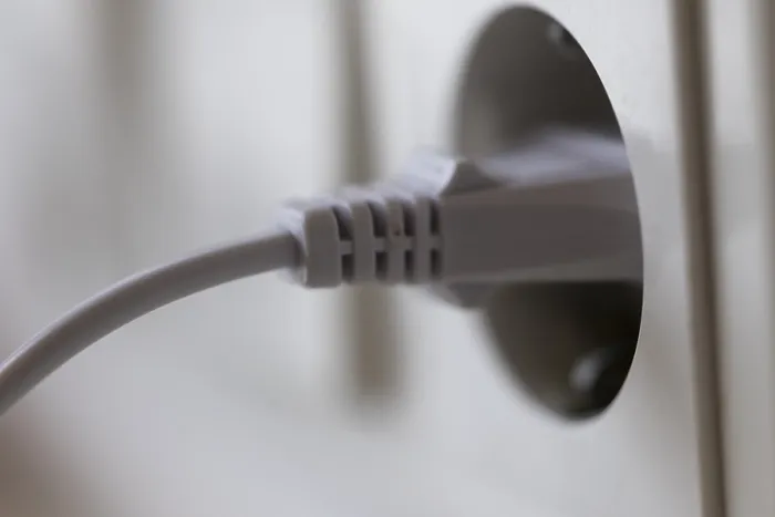 Gerahmter Druck : Weißer Stecker in einer Steckdose an der Wand. Gerahmter Druck : Weißer Stecker in einer Steckdose an der Wand.