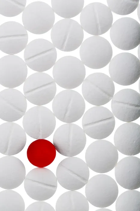 Gerahmter Druck : Weiße Tabletten im Gegensatz zu einer roten Tablette. Gerahmter Druck : Weiße Tabletten im Gegensatz zu einer roten Tablette.
