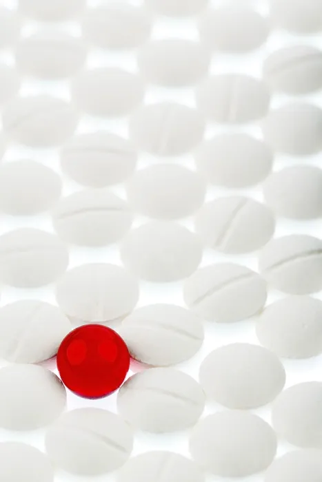 Gerahmter Druck : Weiße Tabletten im Gegensatz zu einer roten Tablette.