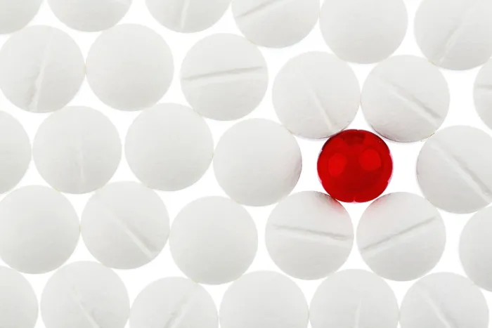 Gerahmter Druck : Weiße Tabletten im Gegensatz zu einer roten Tablette. Gerahmter Druck : Weiße Tabletten im Gegensatz zu einer roten Tablette.