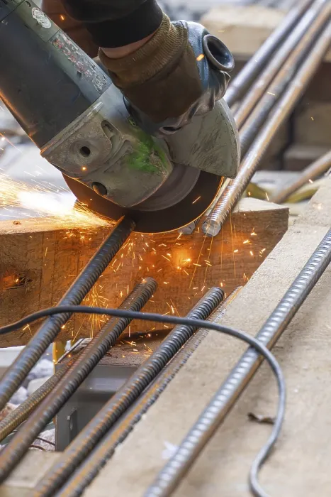 Gerahmter Druck : Ein Arbeiter schneidet Metallstangen mit einem Flex. Gerahmter Druck : Ein Arbeiter schneidet Metallstangen mit einem Flex.