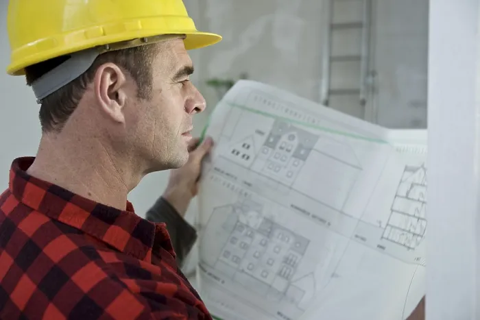 Gerahmter Druck : Arbeiter mit einem harten Helm, der sich auf einen Bauplan konzentriert. Gerahmter Druck : Arbeiter mit einem harten Helm, der sich auf einen Bauplan konzentriert.