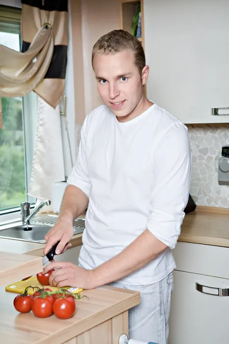 Gerahmter Druck : Jüngerer Mann schneidet Tomaten in der Küche. Gerahmter Druck : Jüngerer Mann schneidet Tomaten in der Küche.