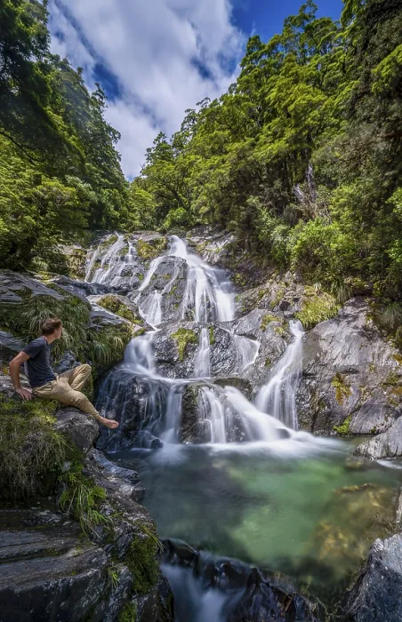 Gerahmter Druck : Jüngerer Mann sitzt an einem Wasserfall.