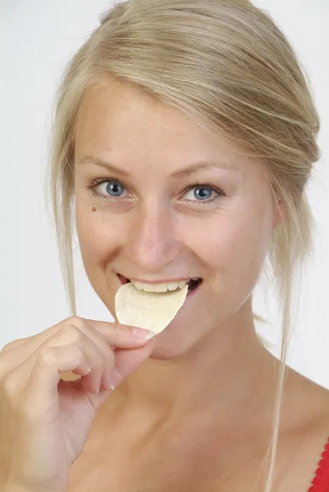 Gerahmter Druck : Junge Frau isst Chips. Gerahmter Druck : Junge Frau isst Chips.