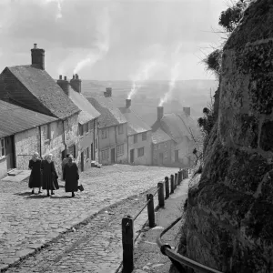Gold Hill Print, a photograph of women walking down a steep cobbled road in Shaftesbury