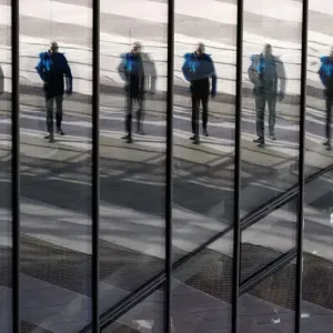 A man is reflected in the glass facade of the Post Tower A man is reflected in the glass facade of the Post Tower