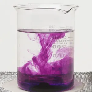 Glass beaker containing potassium manganate shows the solid dissolving to form a solution