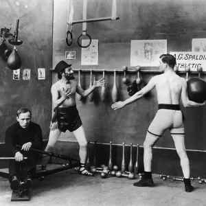 Old Time Gym Print circa 1915: Two men in boxer shorts toss a medicine ball