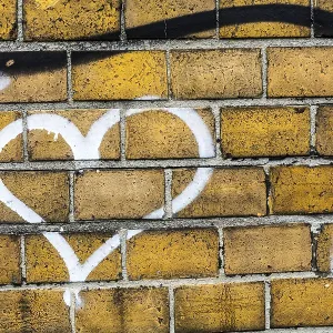 Un grafiti de corazón en una pared de ladrillo.