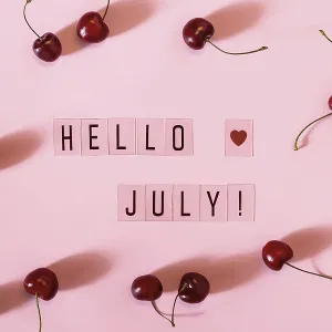 Hola texto de julio y dispersión de cereza morada sobre fondo rosa.