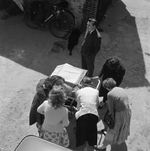 Drucke von Thaxted, Essex. Blick auf eine Gruppe von Frauen die ein Baby im Wagen betrachten und sich über es unterhalten während ein Mann sie beobachtet wird. Fotografiert von John Gay Ende der 1950er Jahre England damals und heute – Historischer Wandel im Laufe der Zeit: Ein neuer Baby a089549