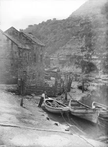 Drucke von Staithes Beck, Loftus, Redcar und Cleveland. Ein Mann steht neben einem an der Seemeerung befestigten Ruderboot. Fotografiert im frühen zwanzigsten Jahrhundert von Edwin Dockree England damals und heute – Historischer Wandel im Laufe der Zeit: Staithes Beck B 57 2002