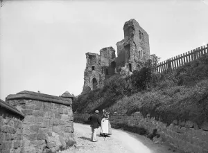 Drucke von SCHLOSS SCARBOURGH, NORD-YORK-SHIRE. Ein älteres Paar im Gespräch auf einer Gasse neben dem Turm von Schloss Scarborugh Historische Fotos aus England – Menschen, Orte und Alltag: Schloss Scarborough Cc76 00637