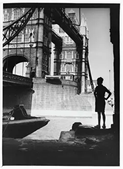 Drucke von Ein Junge steht im Schatten von Tower Bridge in London, um es zu bewundern Tower Bridge Drucke: Junge und Tower Bridge