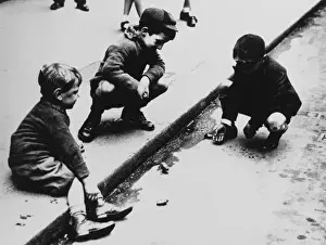 Drei Jungen spielen Münzen im Schmutzwasser