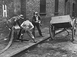 WW2 Firefighters In Action Drucke: Connecting up a hosepipe during the Blitz