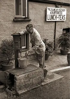 Ein Mann füllt einen Eimer an einem Wasserstandpumpen