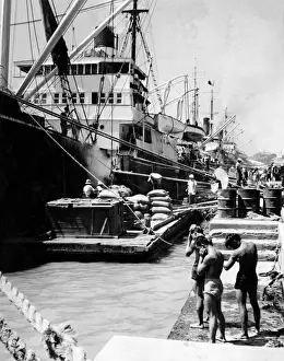 Drucke von Entladung einer Fracht von Schiffen auf den Hafen von Manila (Philippinen). Drei junge Männer mit Shorts schütteln sich vor der Hitze ab und trocknen ihr Schweiß vom Körper Verwandte Bilder Drucke: Mannilahäfen