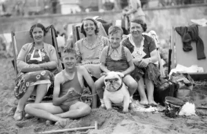 Drucke von An der Strandpromenade von Margate saßen drei Damen auf Hockern. Zwei Jungen im Schwimmbadanzug saßen: einer am Sand und ein anderer auf einem Spielhund Urlauber Genießen Die Vorzüge Der Küstenorte In Kent Und Sussex Drucke: Am Strand von Margate, Ende der 1920er Jahre