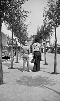 Summer Leisure Activities Drucke: Two people walking along a tree-lined pavement