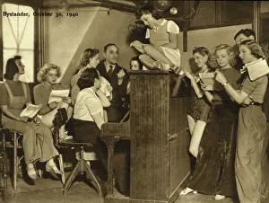 Drucke von Ernst Wöbburn sitzt am Klavier und übt mit den Mädchen des Revue-Theaters in der Windmühle von London im Jahr 1940 Theater Drucke: Der Turmwindmühlen-Theater, 1940