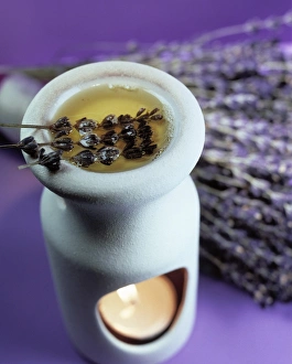 Drucke von Aromatherapien. Trockener Lavendel (Lavendula sp.) und dessen ätherisches Öl in einem Ölabrenner. Hinter dem Korb ist eine Handvoll von Lavendel zu sehen Bilder Datiert 2003 April: Aromatherapy