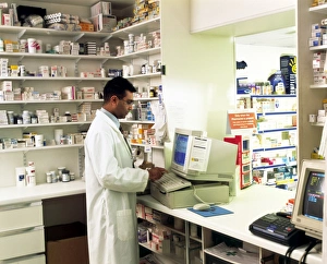 Drucke von MODELL FREIGEBEN. Apotheker. Blick auf einen Apotheker, der mit einem Computer ein Patientenunterlagenformular ausfüllt Bilder Datiert 2003 September: Apotheker verwendet einen Computer im Apotheken