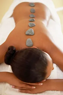 Drucke von MODELL FREIGEBEN. Steintherapie. Die Frau liegt auf dem Bauch mit Steinplatten entlang ihrer Wirbelsäule platziert. Die Platten werden erhitzt, um die Muskeln der Rücken zu erwärmen Schlafzimmer Drucke: Steintherapie