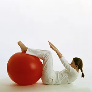 Drucke von MODER releaseert. Eine Frau nutzt ein Übungsball (Schweizer Ball) für Sitzuppsätze. Mit diesem Gegenstand können eine Vielzahl von Übungen durchgeführt werden Bilder Datiert 2003 März: Frau nutzt eine Dehnkugel