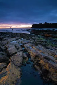 Sonnenuntergang über Kings Edwards Bucht aus der Nähe von Sharpness Point gesehen. Die Reste des Tynemouth Priorats können zu sehen werden, dass sie die Küste umgeben