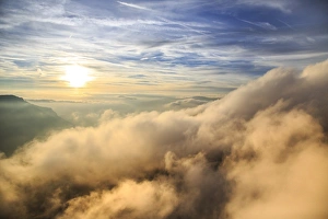 Cloudy Mountain Scenery Europe Drucke: Aerial view of the mountain range of Odle surrounded by clouds, Dolomites, Val Funes