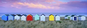 Farbenfroh bemerkenswerte Strandhäuschen und Sanddünen am Sonnenaufgang in Südwestengland
