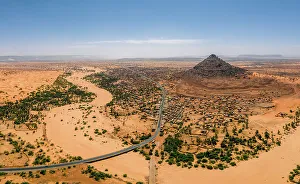 Ein zusammenbrechender Berg eine Flussbett Palmen und Dunen umgeben das Dorf Kamour in der Mauritanien im Sahara-Desert an der westlichen Afrika