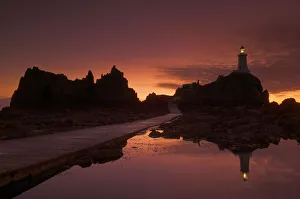 European Island Getaways Drucke: Dramatic sunset, low tide, Corbiere lighthouse, St. Ouens, Jersey, Channel Islands