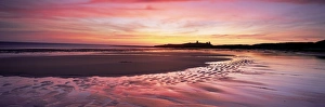 Embleton Bucht am Sonnenaufgang bei niedrigem Wasserstand mit Dunstansburger Schloss im Hintergrund