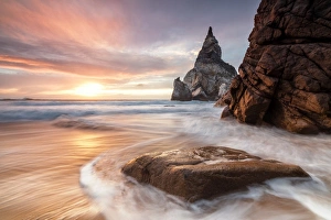 Colorful Coastal Scene Drucke: The fiery sky at sunset is reflected on the ocean waves and cliffs, Praia da Ursa