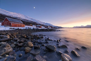 Lyngen Alps Norway Drucke: Fiery sky at sunset and typical Rorbu, snowy peaks and frozen sea, Djupvik, Lyngen Alps