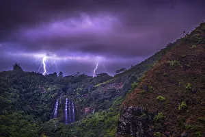 Blitze zucken hinter den Wasserfällen von Opekaa auf der Insel Kauai in Hawaii im Vereinigten Staaten von Amerika am Pazifik