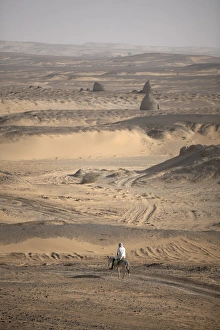Northern Africa Images Drucke: A man on mule-back traverses the desert around