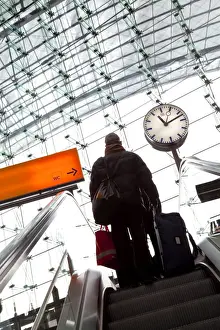 European Transportation Systems Drucke: Passenger on escalator and platform clock at modern train station, Berlin