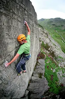 Ein Kletterer macht den ersten Aufstieg auf die Klippen über dem Llyn Padarn-Pass