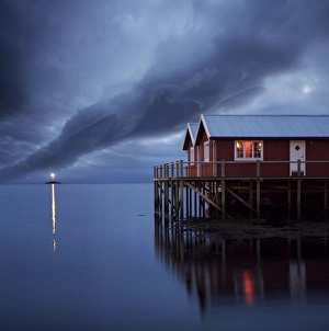 Norwegian Nature Scenes Drucke: Rorbuer on stilts at dusk with lighthouse, Lofoten Islands, Norway, Scandinavia, Europe