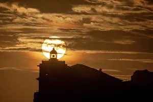 European Coastal Scenery Images Drucke: Sun aligned with the silhouette of the lighthouse of Luarca, Asturias, Spain, Europe