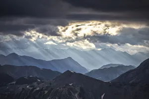 Sonnenstrahlen filtrieren zwischen schwarzen Wolken bei Sonnenaufgang über den Steilpass Stelvio im Naturpark Stelvio in der Region Valtellina in der Provinz Lombardei Italien Süditalien Europa