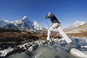 Himalayan Mountains Scenic View Drucke: Trekker crossing a mountain stream, Ama Dablam, 6812m, behind, Solu Khumbu Everest Region